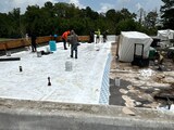 Dickerson Contracting crew in high-visibility vests installing white single-ply membrane on a commercial low-slope roof deck
