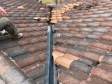 Localized roof repair in progress: tiles lifted along a valley to expose and re-flash the metal valley pan