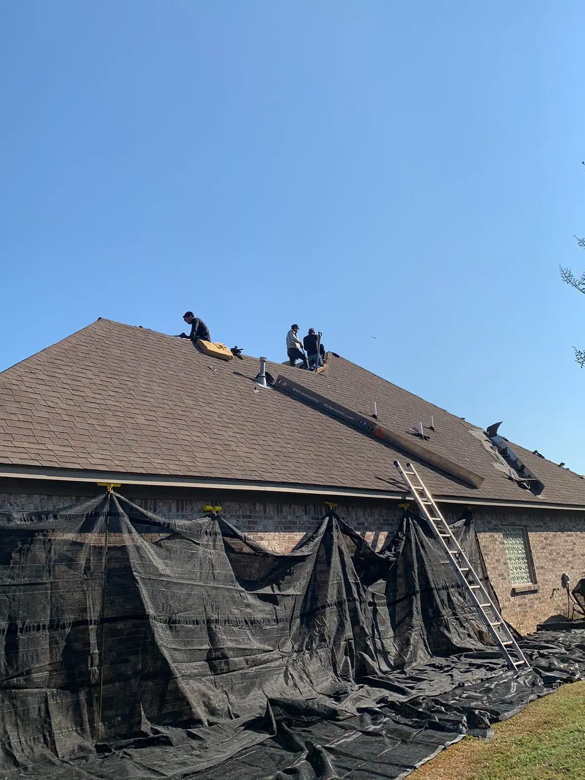 Roofers working on a shingle roof in Madison, MS, by roofing company Dickerson Contracting