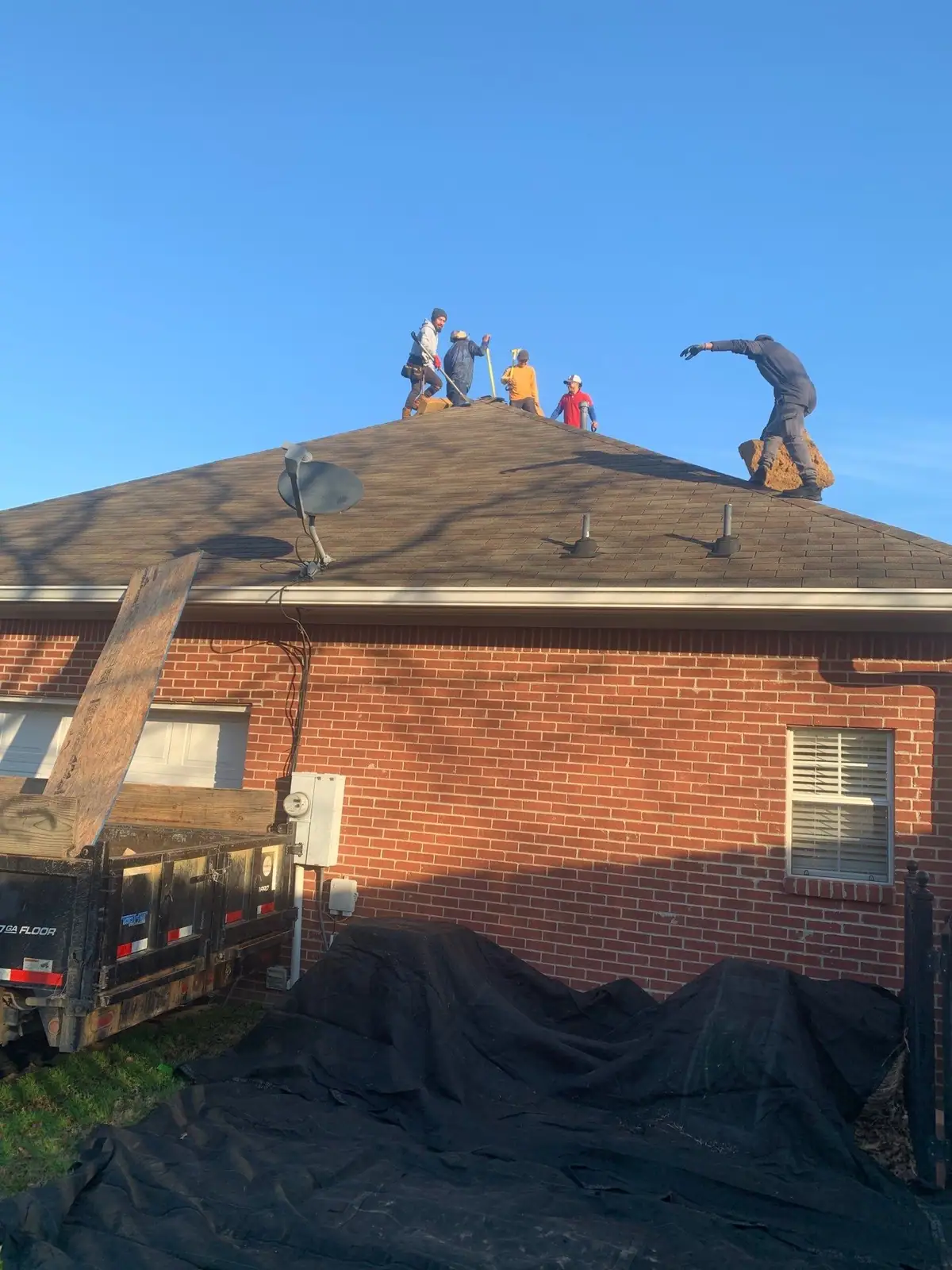 Roofers working on a shingle roof in Brandon, MS, by roofing company Dickerson Contracting