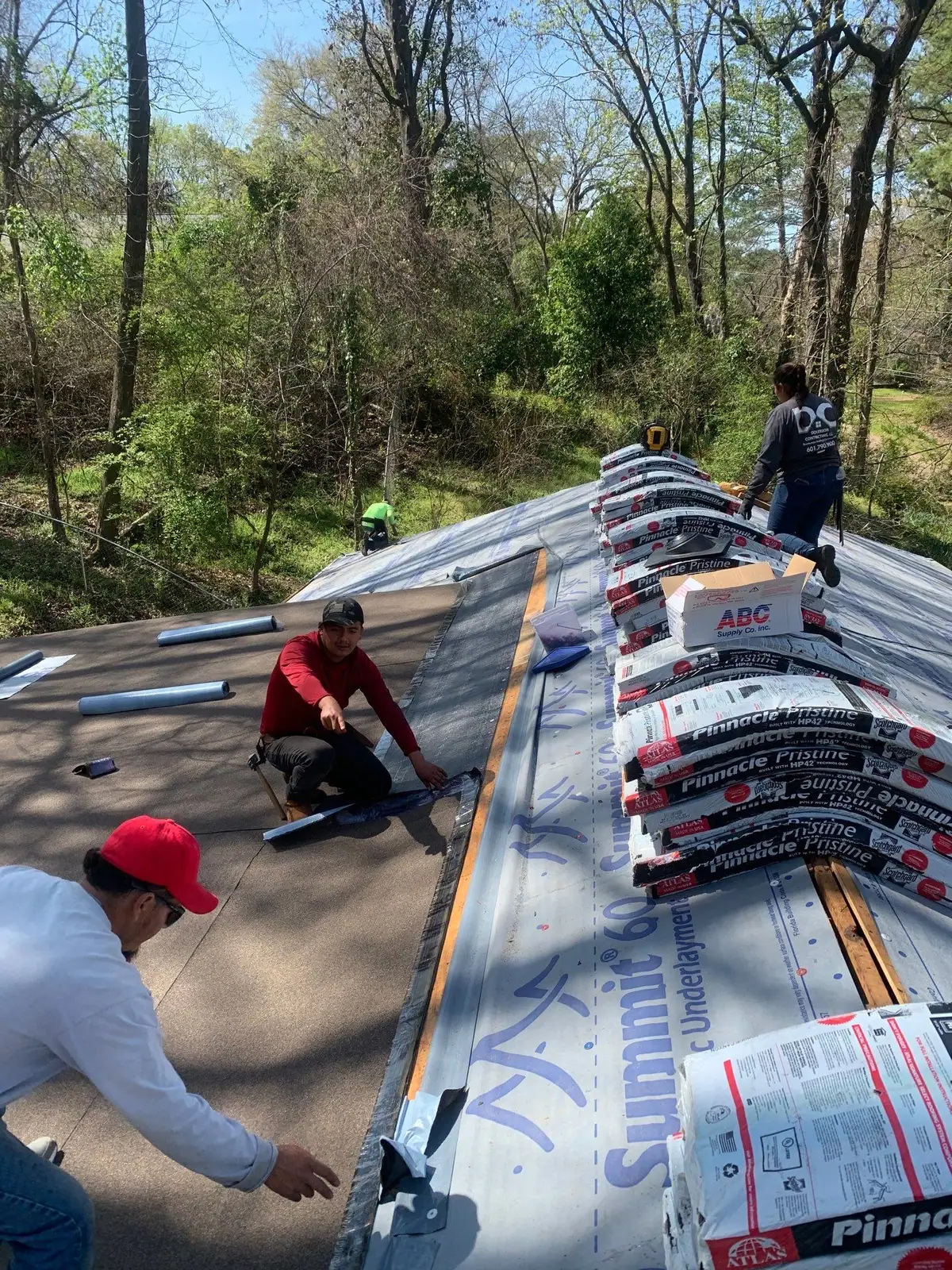Roofers installing new shingles in Clinton, MS, by roofing company Dickerson Contracting
