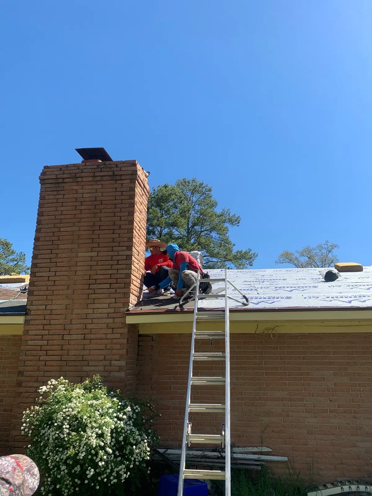 Roofers working across a flat membrane roof, commercial roofing by Dickerson Contracting in Brandon, MS