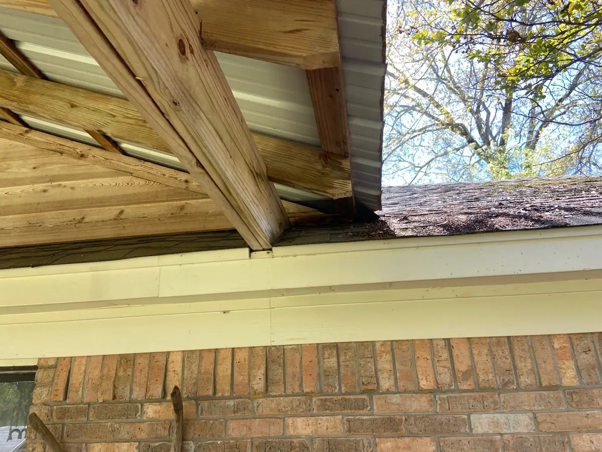 Porch eave opened up, showing rafter tails behind the old soffit