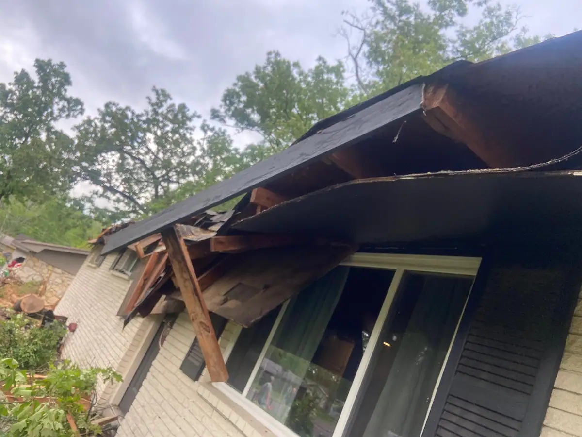 Roof edge, fascia and soffit torn open by a fallen tree over a back door