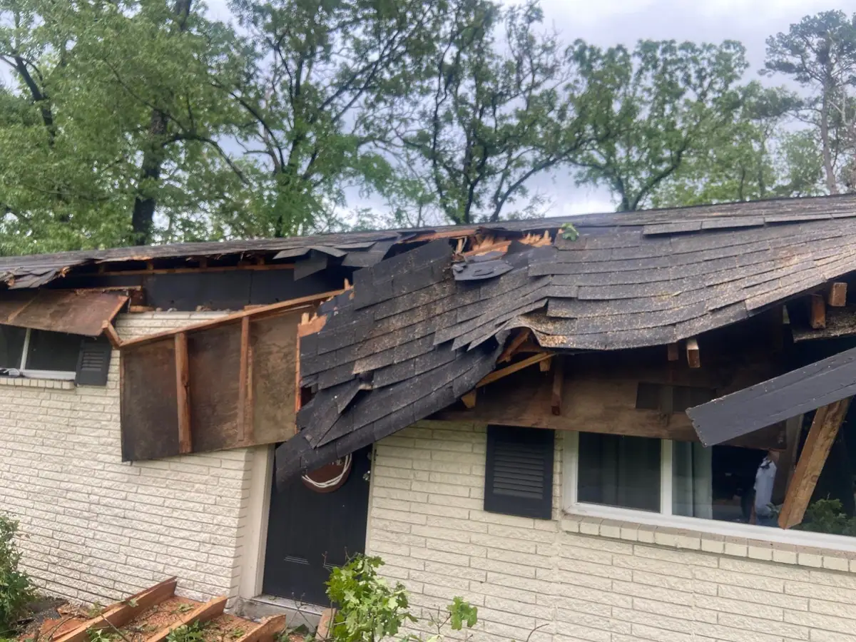 Storm-torn eave and roof edge on a brick home, storm damage for roof repair