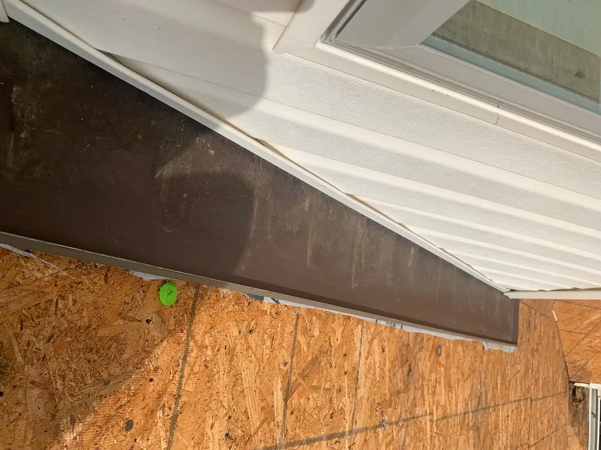 Old fascia wrap and soffit edge above bare wall sheathing, before replacement