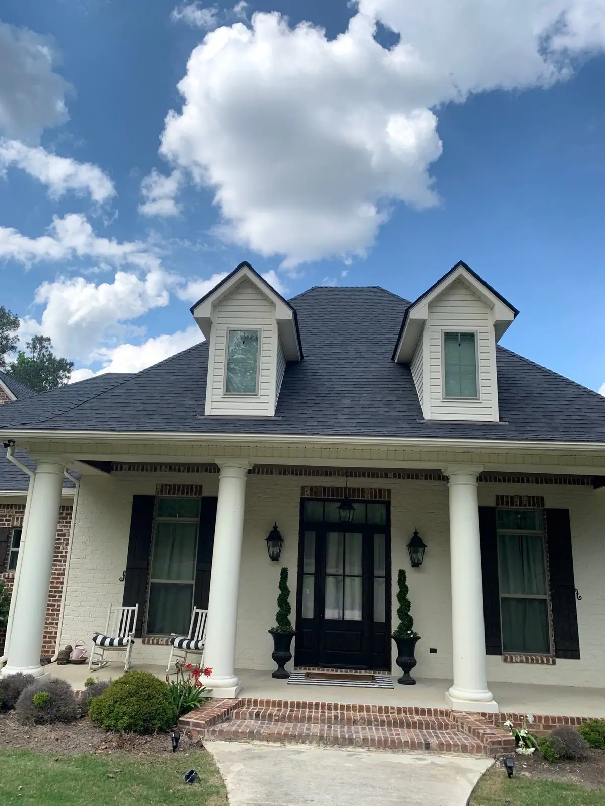 White Acadian-style home with dormers and a new dark shingle roof, residential roofing by Dickerson Contracting
