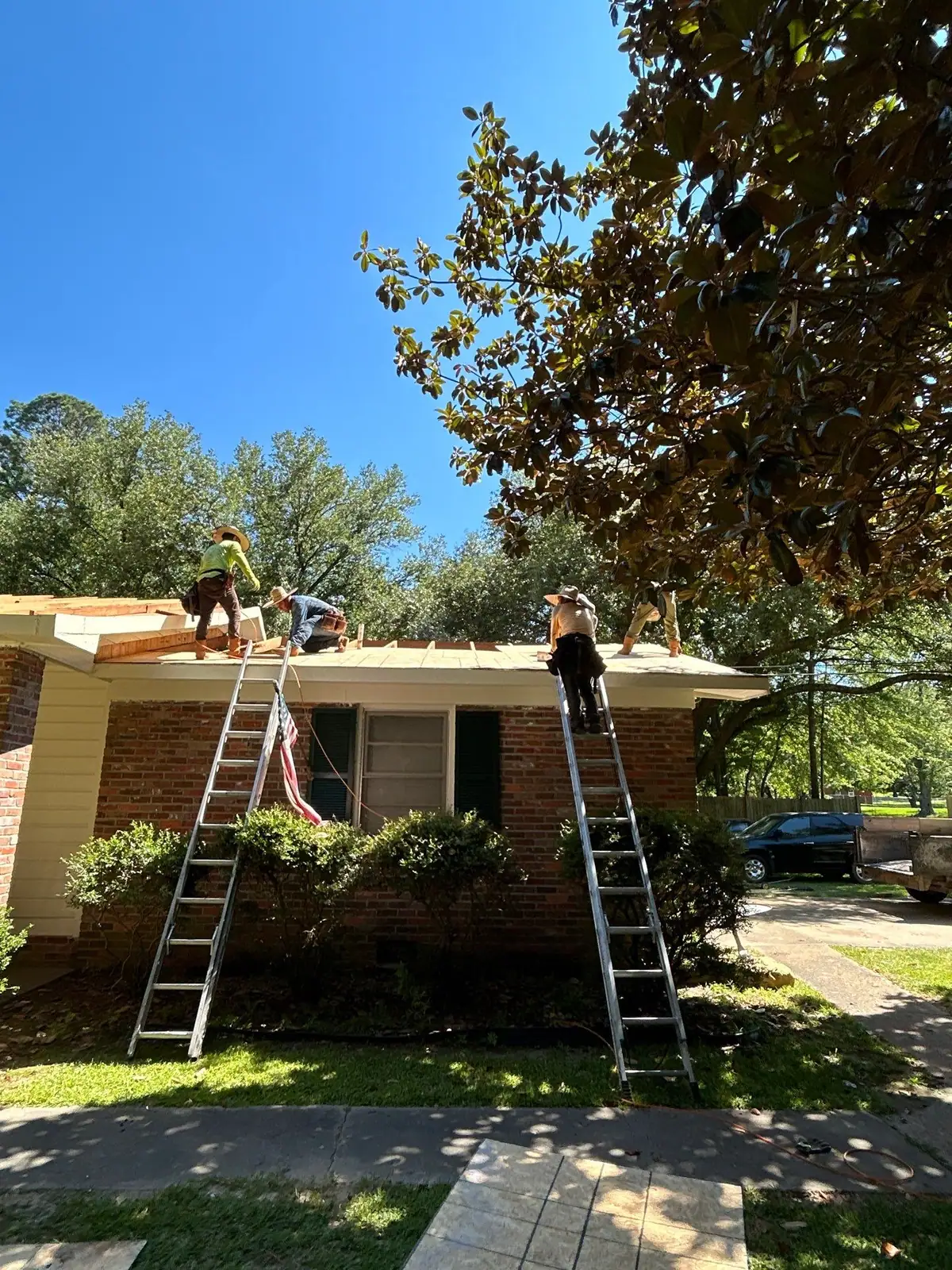Roofers working on a shingle roof in Clinton, MS, by roofing company Dickerson Contracting