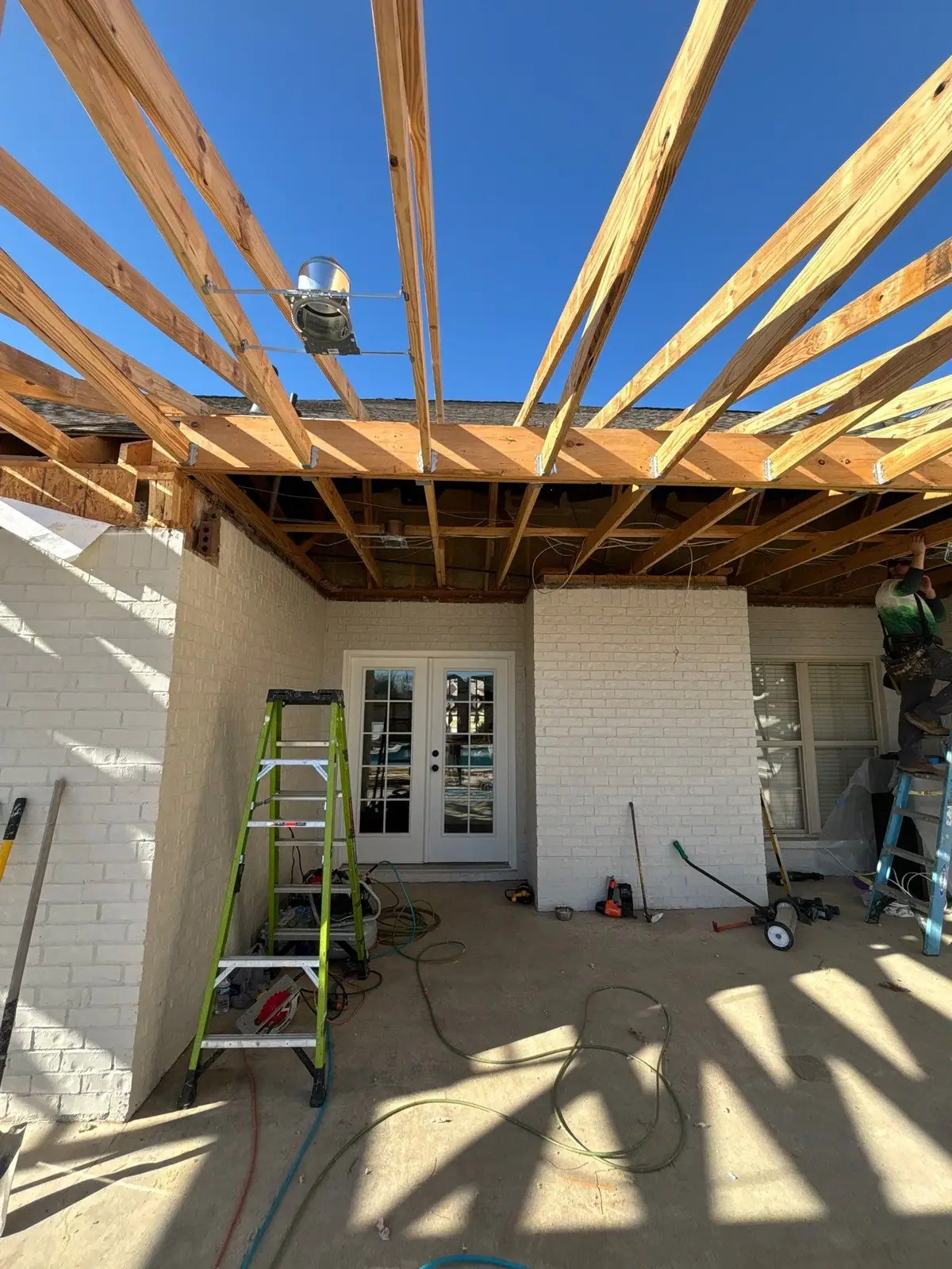 Open rafter framing for a covered patio tied into a brick house, a covered outdoor living space