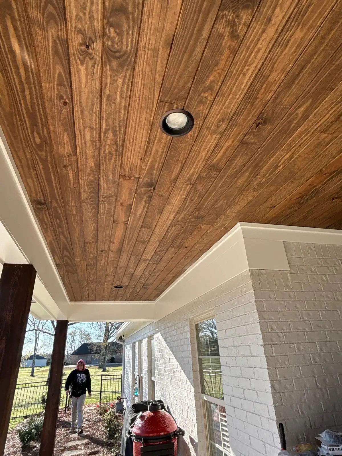 Stained tongue-and-groove ceiling with a recessed light on a covered outdoor living porch