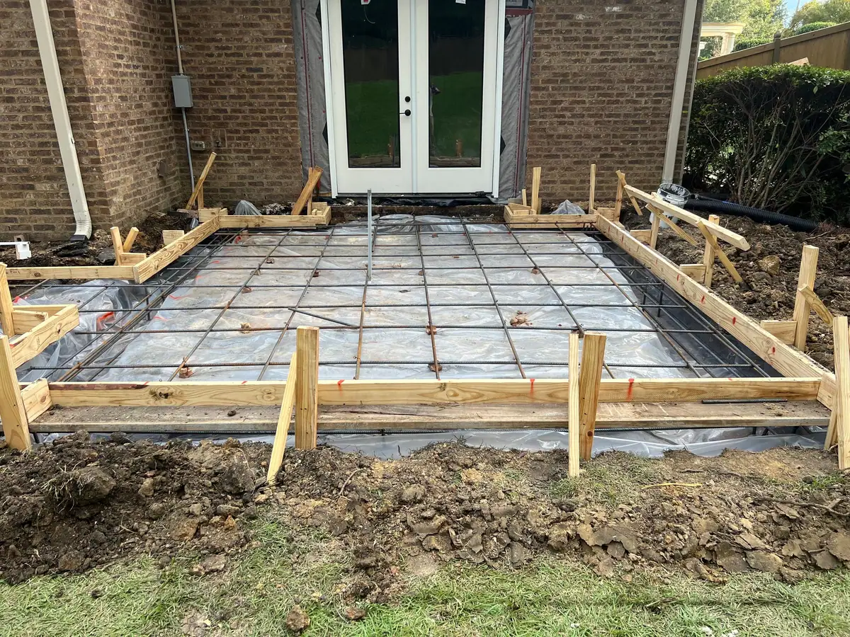 Formed patio slab with rebar over vapor barrier outside French doors, an outdoor living patio
