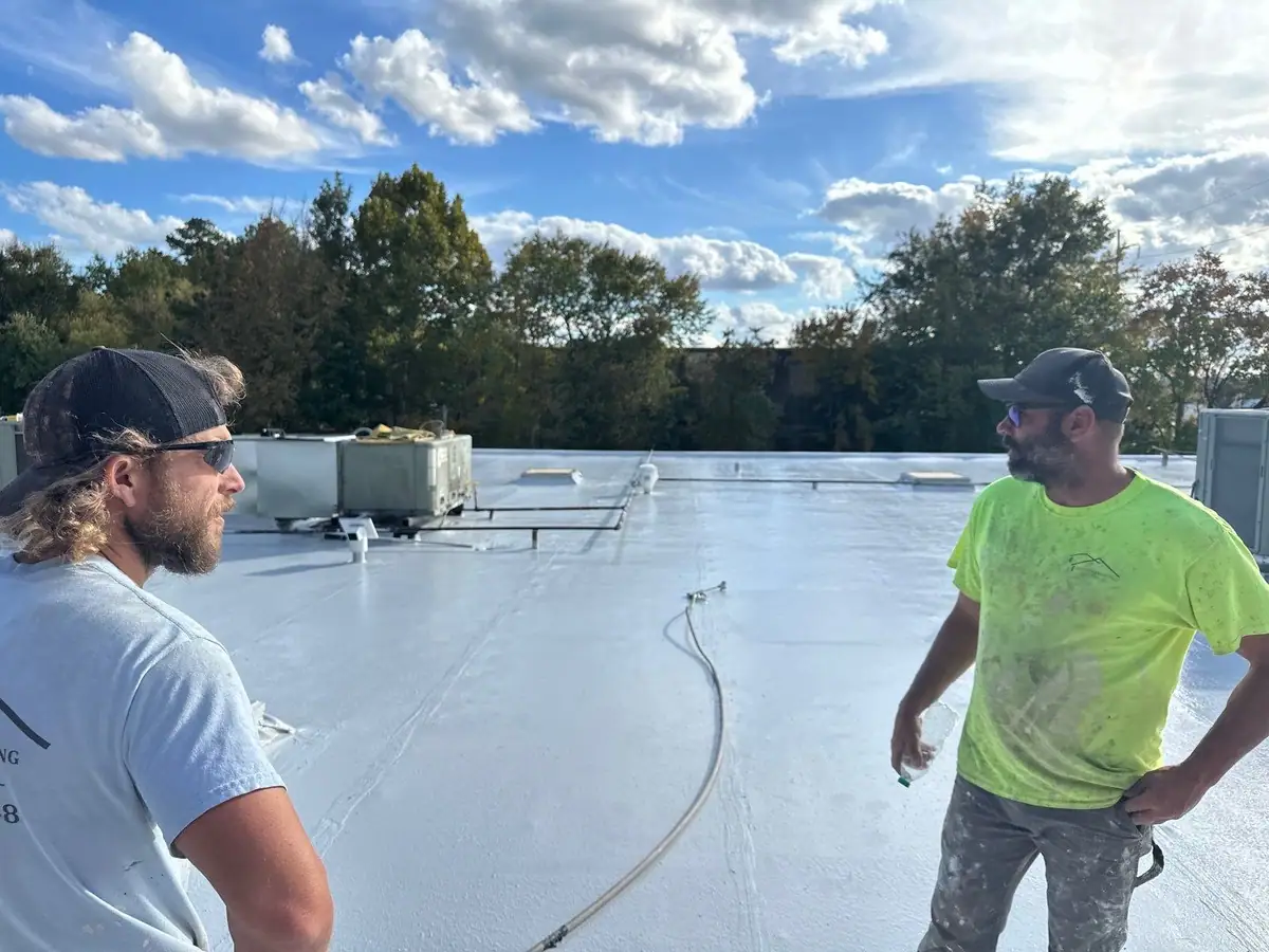 Two roofers walking a finished white TPO commercial roof on a Dickerson Contracting job