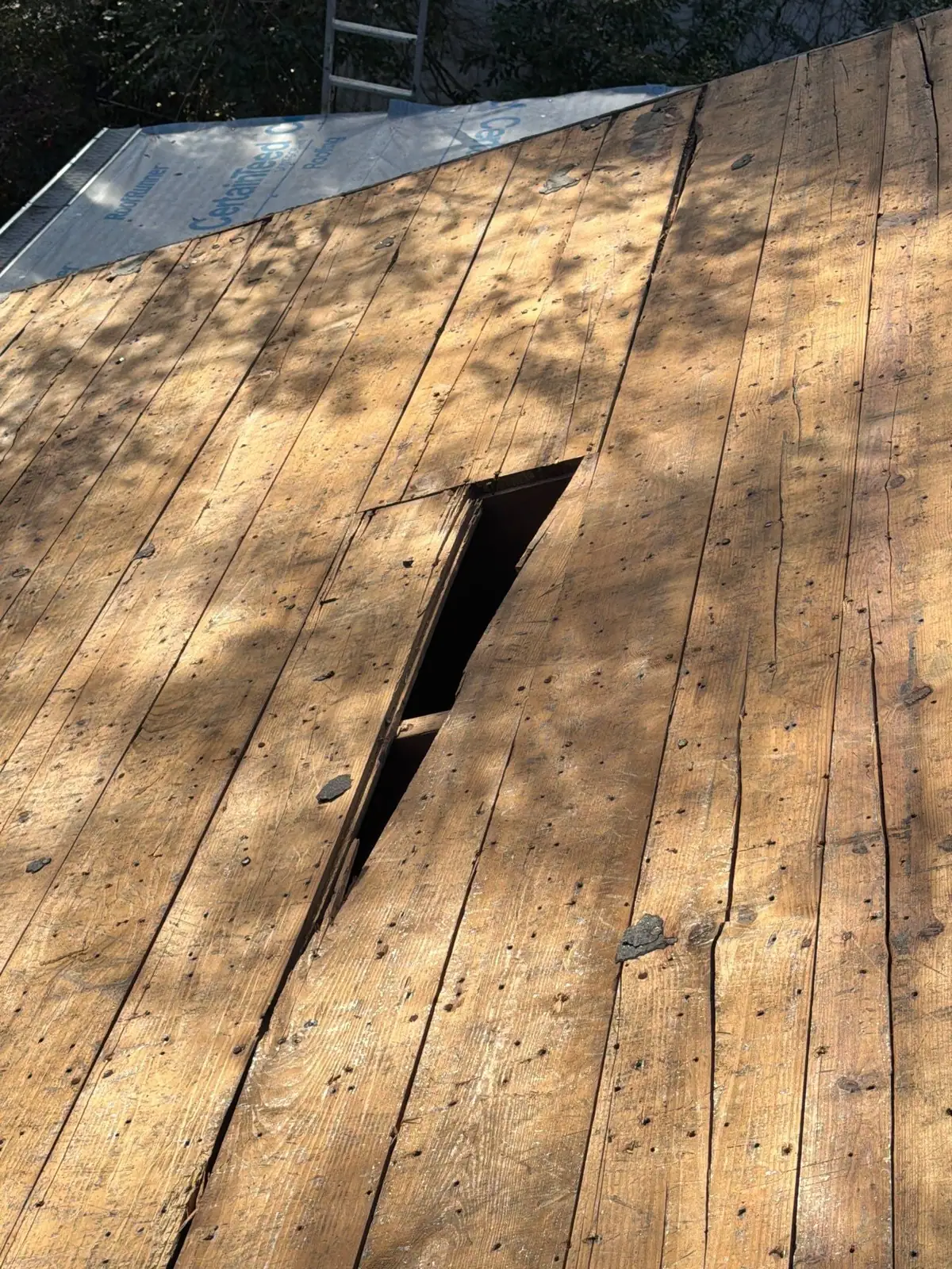 Split decking board exposed during a roof repair once the shingles came off