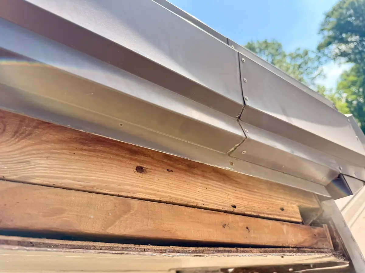 Rotted fascia boards exposed behind metal drip edge