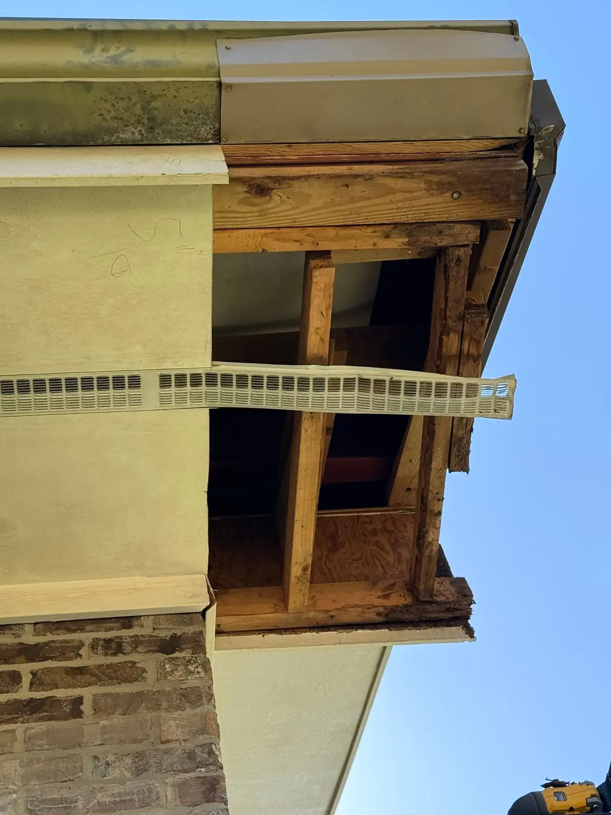Soffit box cut open at a corner, showing water-damaged framing