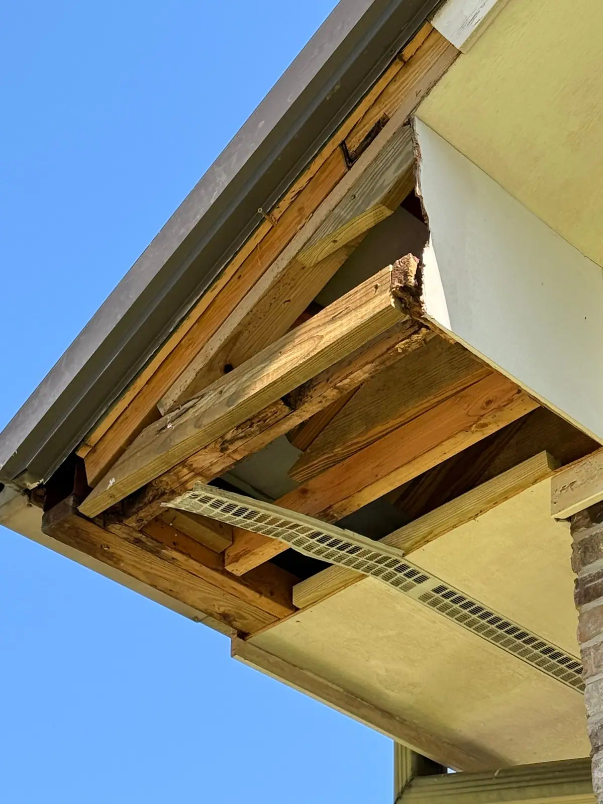 Soffit opened up to show rotted rafter tails and framing behind it