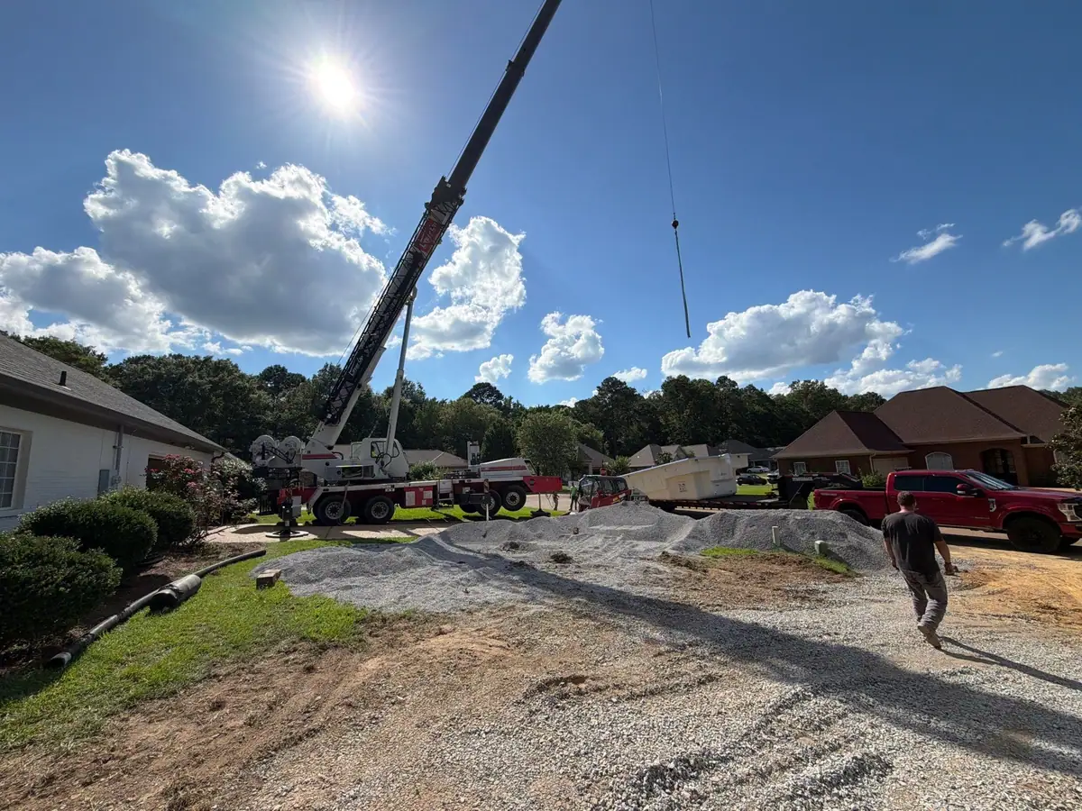 Crane and gravel staged in a front yard on pool install day by DC Pools and Spas, pool company in Brandon, MS