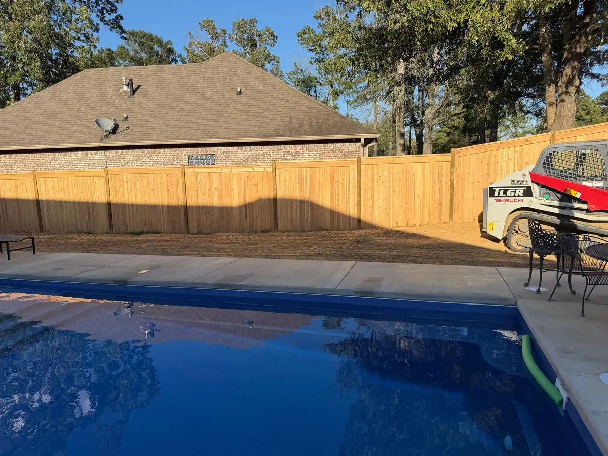 New inground pool beside a freshly built wood privacy fence by DC Pools and Spas serving Pearl, MS