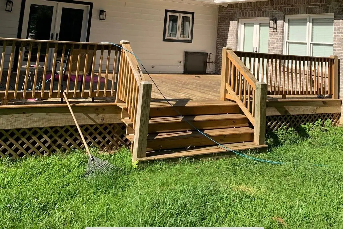 New wood deck with railings and stairs off the back of a brick home for outdoor living