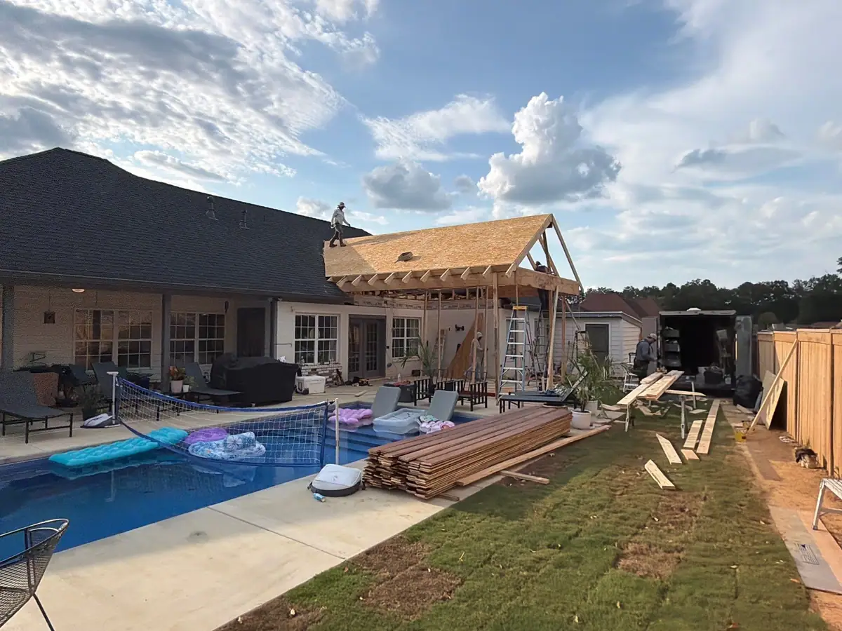 Gable roof framing and decking on the outdoor kitchen pavilion beside a backyard pool