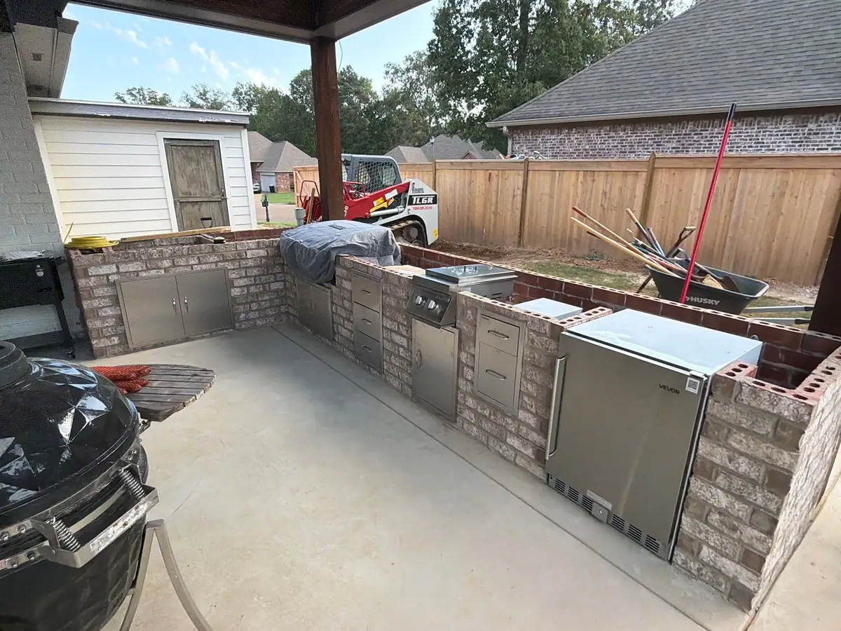 L-shaped brick outdoor kitchen with stainless doors, grill and refrigerator set in the counter