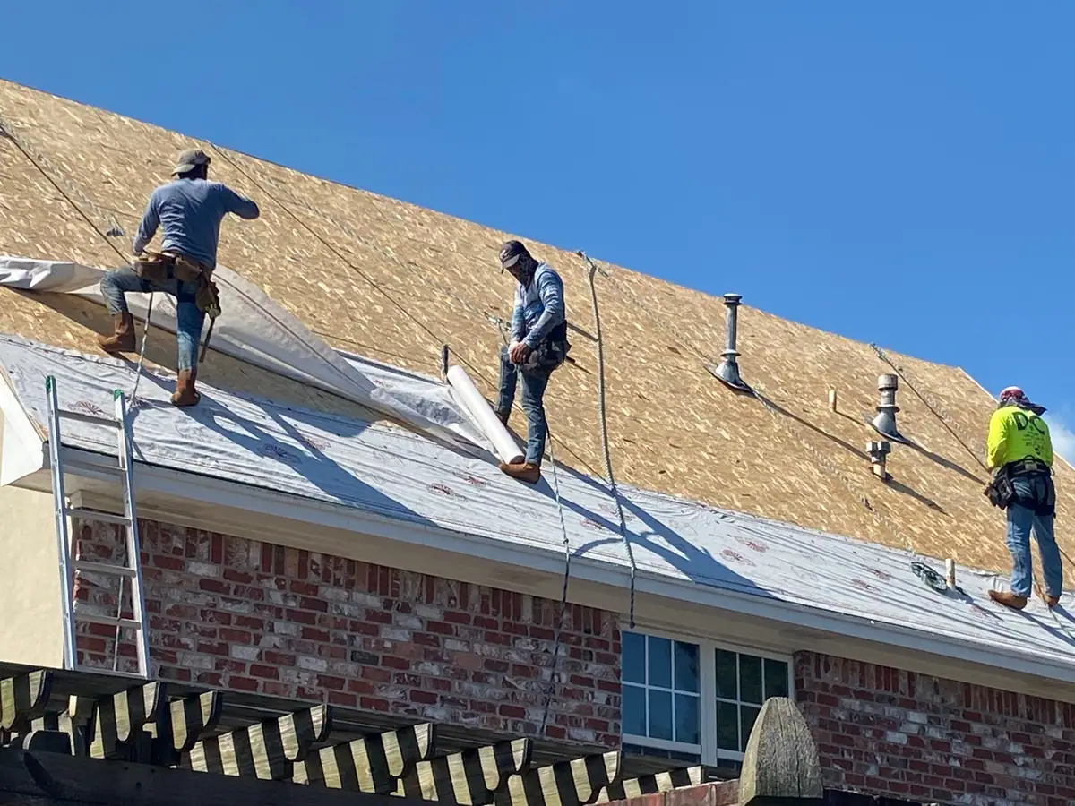 Roofers installing underlayment on a brick two-story home for Dickerson Contracting, a Mississippi roofing company