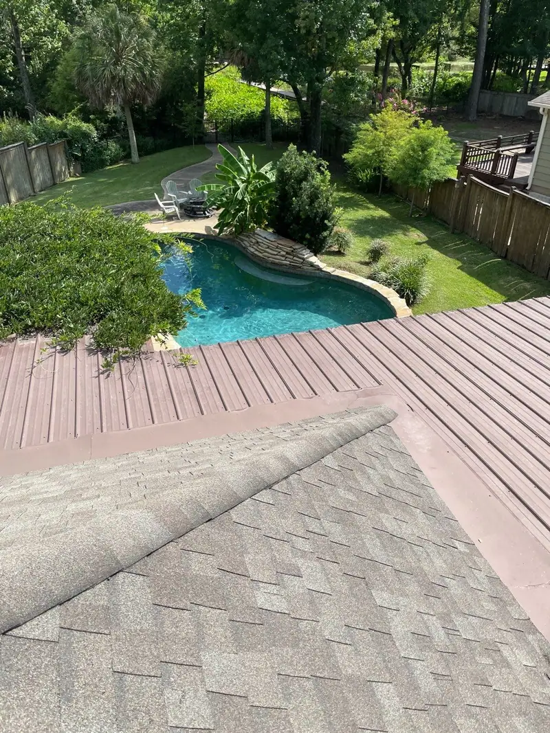 Metal roof section meeting a shingle roof above a backyard pool, metal roofing by Dickerson Contracting in Brandon, MS