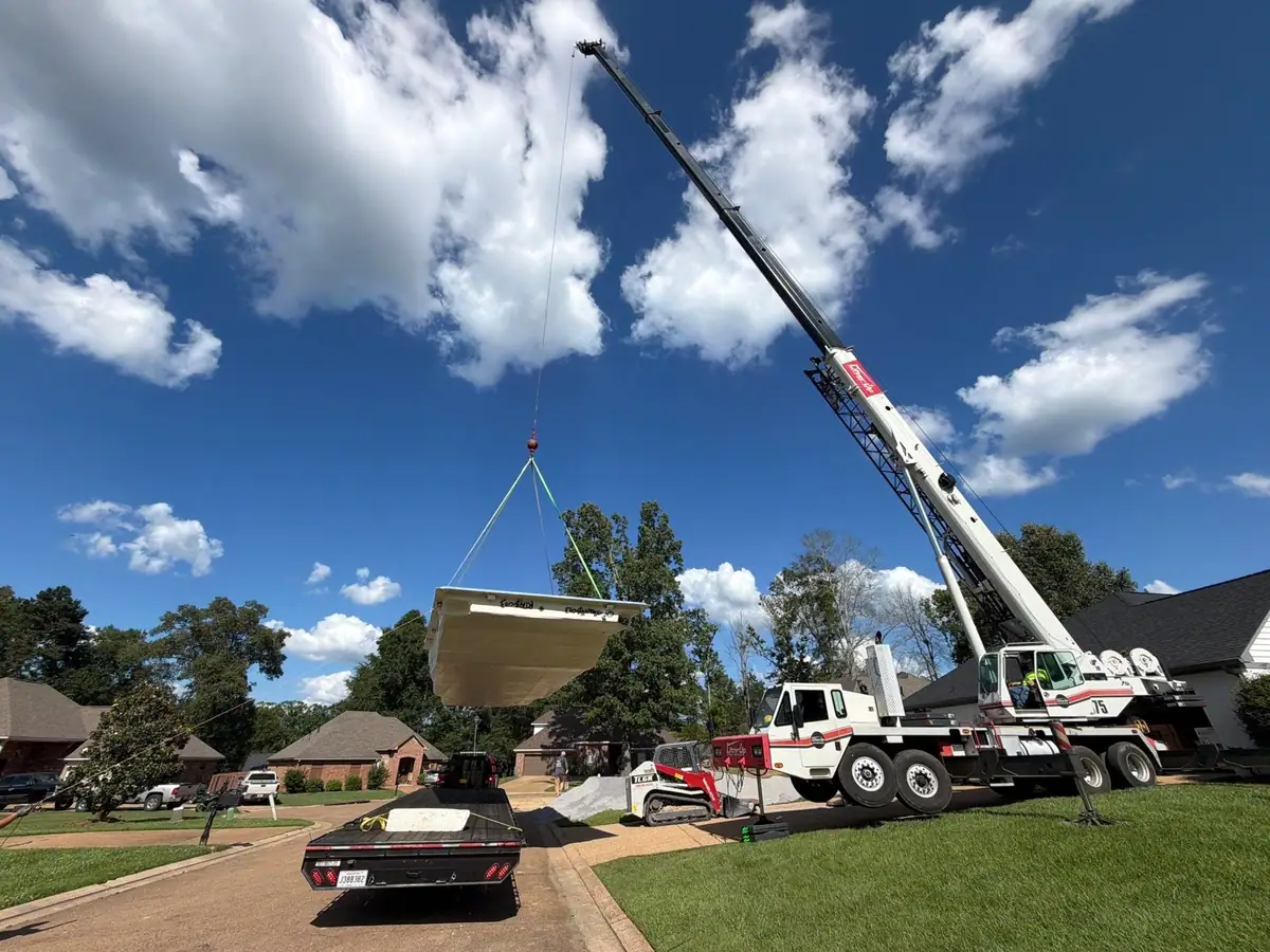 Crane lifting a fiberglass pool shell over the street, fiberglass pool installation serving Flowood, MS