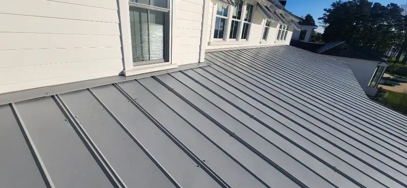 Standing seam metal roof along a white-sided second story, metal roofing by Dickerson Contracting serving Flowood, MS
