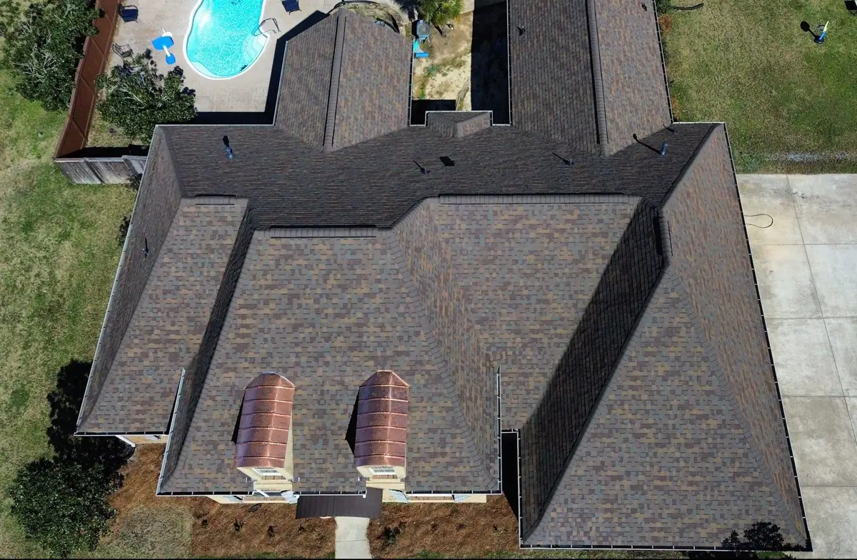 Brick home with copper eyebrow dormers and a new shingle roof, residential roofing by Dickerson Contracting in Flowood, MS