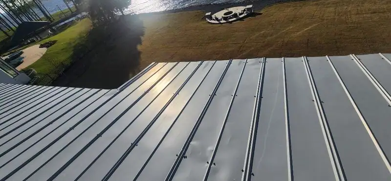 Standing seam metal roof valley above a lakefront lawn, metal roofing by Dickerson Contracting in Madison, MS