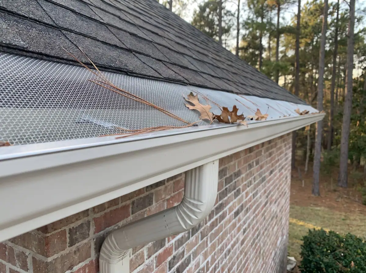 Micro-mesh gutter guard holding leaves and pine needles off a white gutter