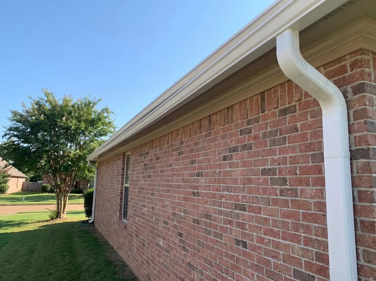 Long white seamless gutter run with one downspout along a brick ranch house, white gutter installation