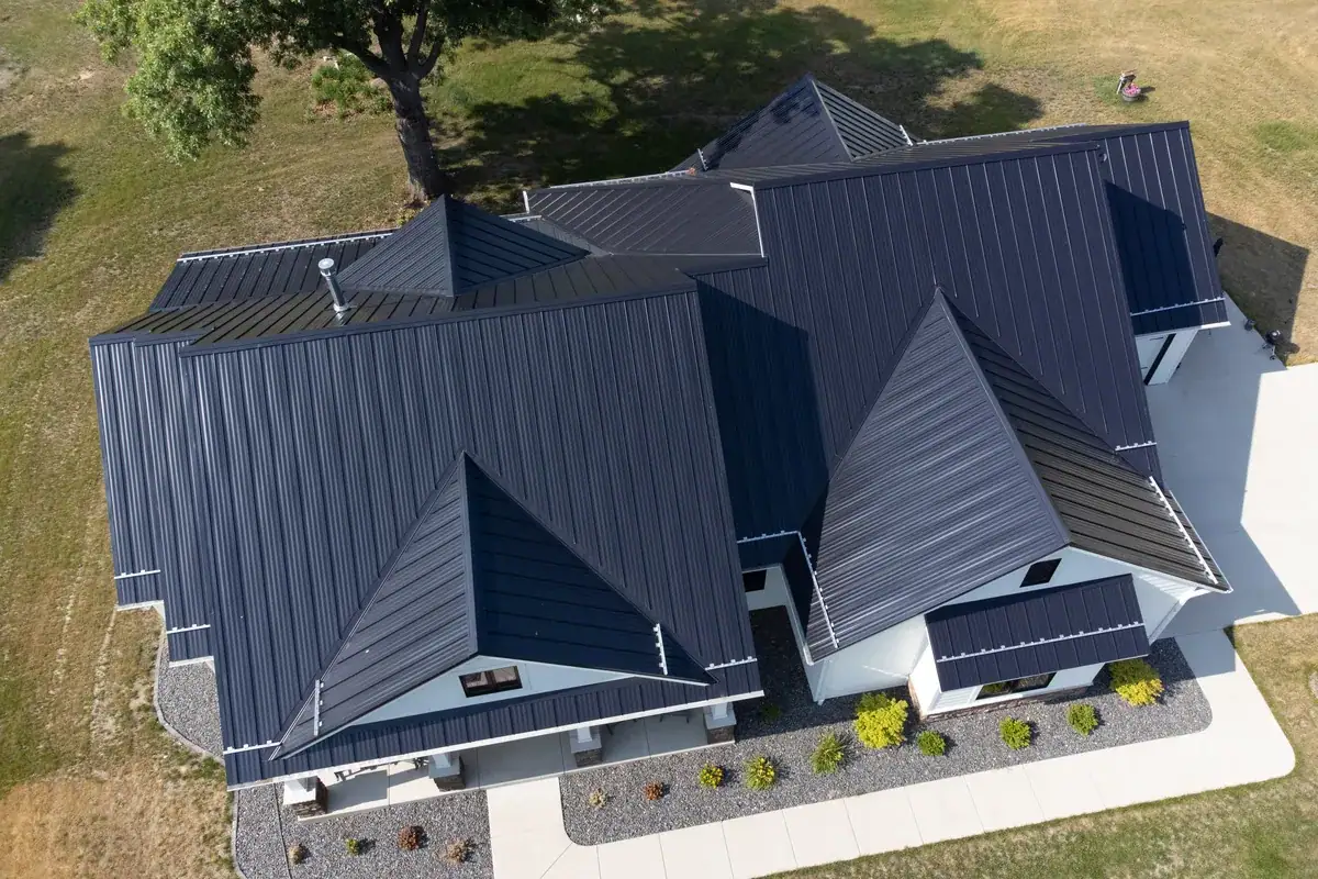 Charcoal standing seam metal roof on a home with multiple hips and gables, seen from above