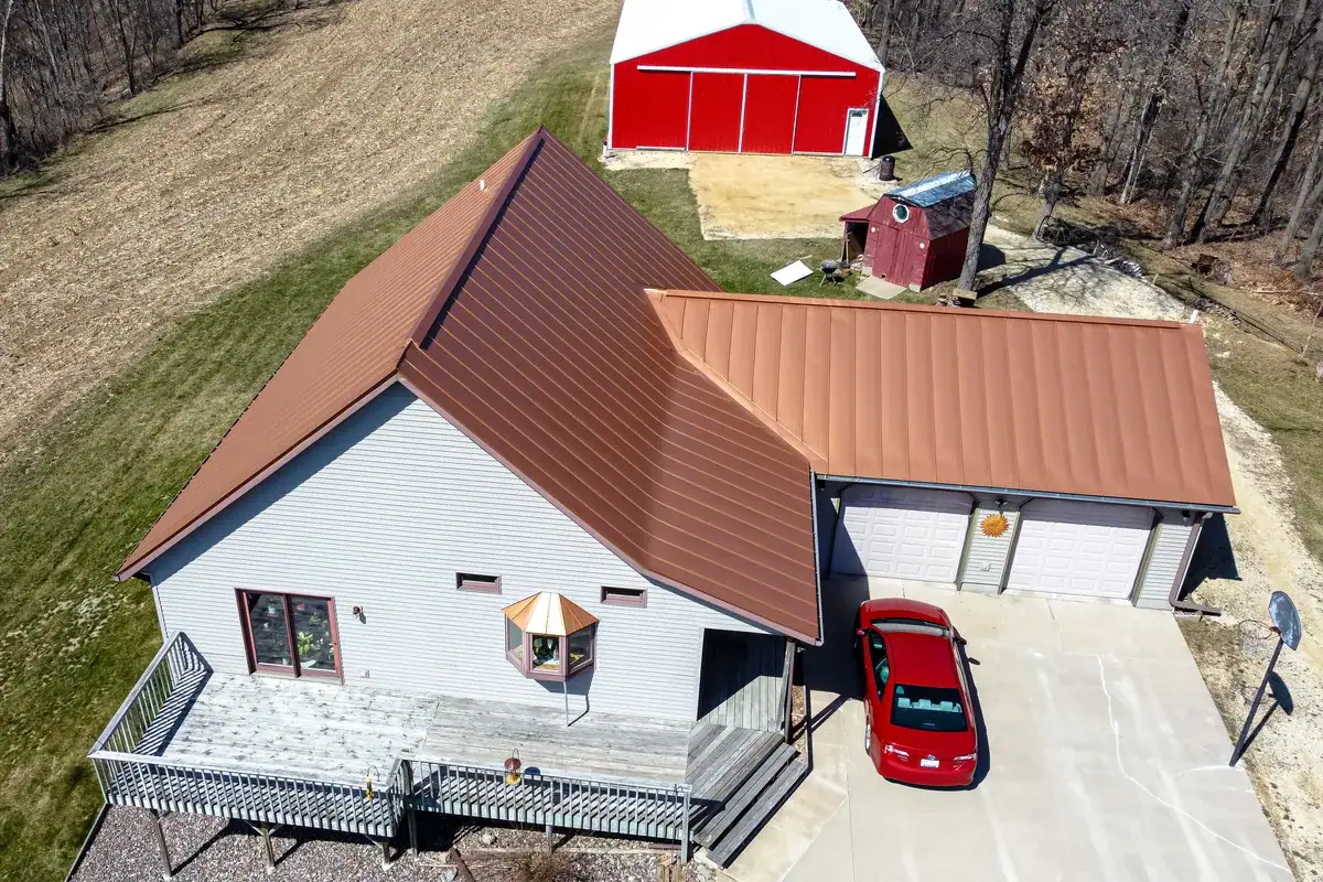 Copper-toned standing seam metal roof on a farmhouse and attached garage