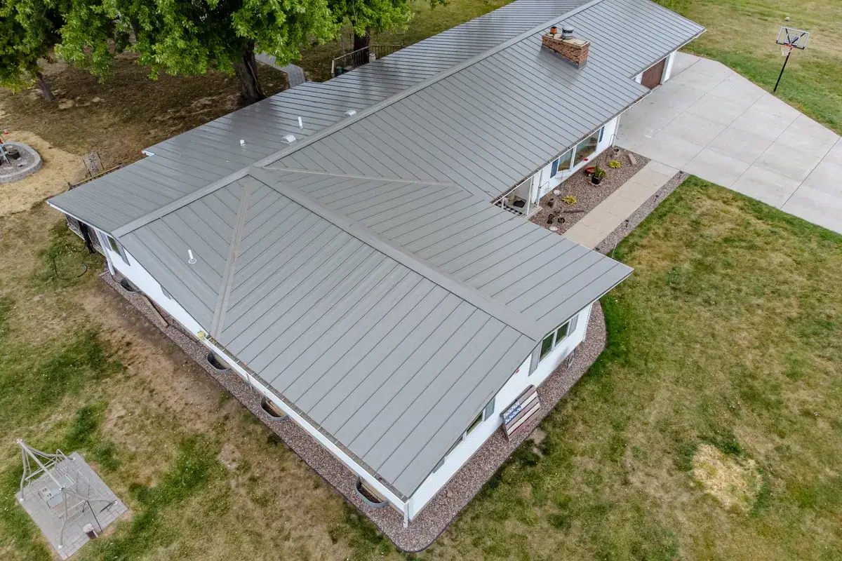 Silver gray standing seam metal roof on a long low-pitch ranch home